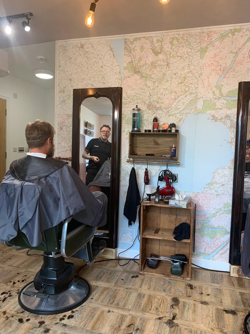 A haircut at Penny Bank, with a traditional framed mirror and large map on the wall